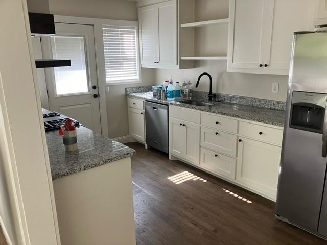 204 E Dry St, San Saba, TX 76877 - kitchen with stainless steel appliances, a sink, open shelves, dark wood-style floors, and white cabinetry