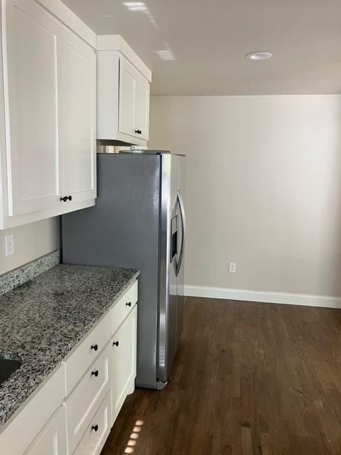 204 E Dry St, San Saba, TX 76877 - kitchen featuring light stone countertops, stainless steel fridge, dark wood-style flooring, white cabinets, and baseboards