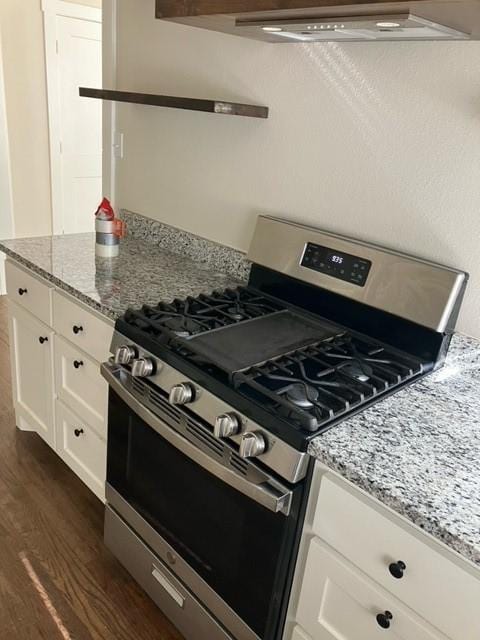 204 E Dry St, San Saba, TX 76877 - kitchen featuring stainless steel range with gas cooktop, dark wood-style floors, white cabinetry, light stone countertops, and range hood