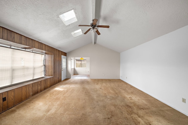1639 Castle Creek Dr, Missouri City, TX 77489 - empty room featuring a ceiling fan, light colored carpet, a skylight, a textured ceiling, and wood walls