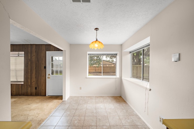 1639 Castle Creek Dr, Missouri City, TX 77489 - unfurnished dining area with wood walls, a textured ceiling, light tile patterned floors, and baseboards