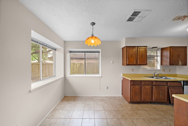 1639 Castle Creek Dr, Missouri City, TX 77489 - kitchen featuring a sink, light countertops, brown cabinetry, decorative light fixtures, and a textured ceiling