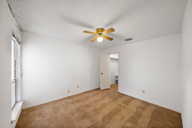 1639 Castle Creek Dr, Missouri City, TX 77489 - unfurnished bedroom featuring light colored carpet, a ceiling fan, a textured ceiling, and a walk in closet