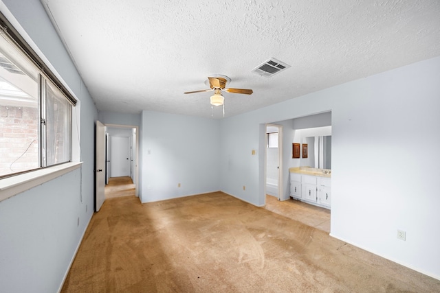 1639 Castle Creek Dr, Missouri City, TX 77489 - unfurnished bedroom featuring light carpet, a textured ceiling, connected bathroom, and a ceiling fan