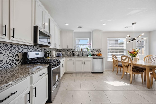 10123 Twila Springs Ct, Houston, TX 77095 - kitchen with appliances with stainless steel finishes, a chandelier, decorative backsplash, light stone counters, and white cabinets