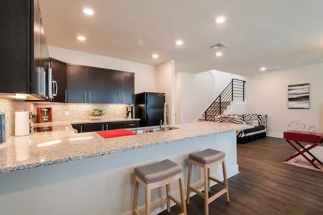 442 William D Fitch, College Station, TX 77845 - kitchen with freestanding refrigerator, a breakfast bar area, a peninsula, tasteful backsplash, and dark wood-style floors