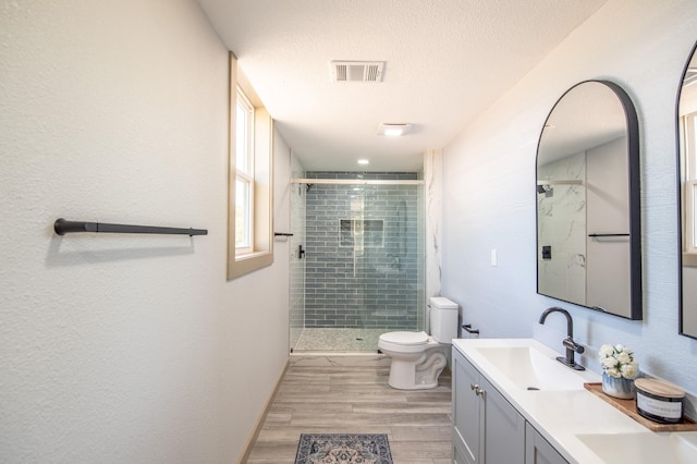 103 Whispering Oaks, Somerville, TX 77879 - bathroom with toilet, a shower stall, double vanity, wood finished floors, and a textured ceiling