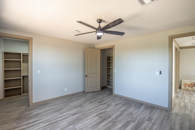 103 Whispering Oaks, Somerville, TX 77879 - unfurnished bedroom with wood finished floors, baseboards, a closet, ceiling fan, and a spacious closet