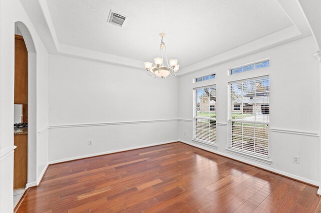 3303 Hickory Knoll Dr, Pearland, TX 77581 - empty room featuring a tray ceiling, a chandelier, wood finished floors, arched walkways, and baseboards