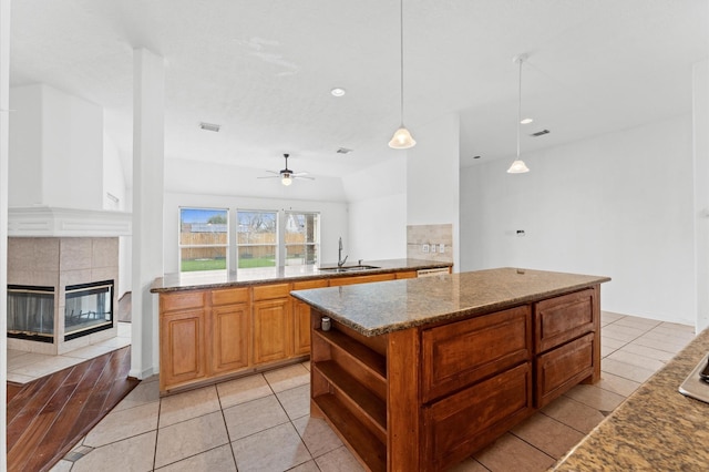3303 Hickory Knoll Dr, Pearland, TX 77581 - kitchen featuring a sink, a fireplace, open shelves, dark stone counters, and a center island