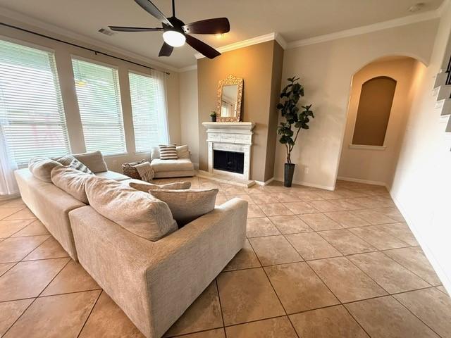 1216 Matthew Hills Ln, Spring, TX 77386 - living room featuring crown molding, light tile patterned flooring, ceiling fan, a fireplace, and arched walkways
