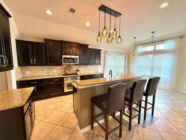 1216 Matthew Hills Ln, Spring, TX 77386 - kitchen featuring stainless steel appliances, light tile patterned floors, a kitchen bar, tasteful backsplash, and recessed lighting