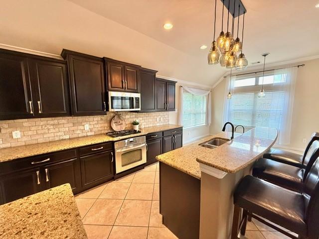 1216 Matthew Hills Ln, Spring, TX 77386 - kitchen with stainless steel appliances, a sink, backsplash, decorative light fixtures, and a breakfast bar area
