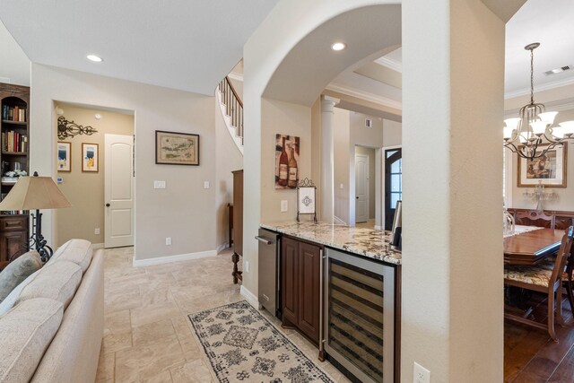 5131 Rowley Falls Ln, Sugar Land, TX 77479 - bar featuring wine cooler, crown molding, arched walkways, hanging light fixtures, and baseboards