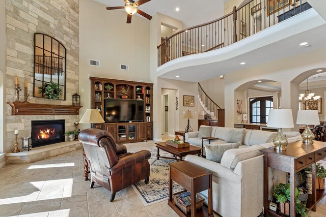 5131 Rowley Falls Ln, Sugar Land, TX 77479 - living room with arched walkways, a stone fireplace, stairs, a ceiling fan, and a high ceiling