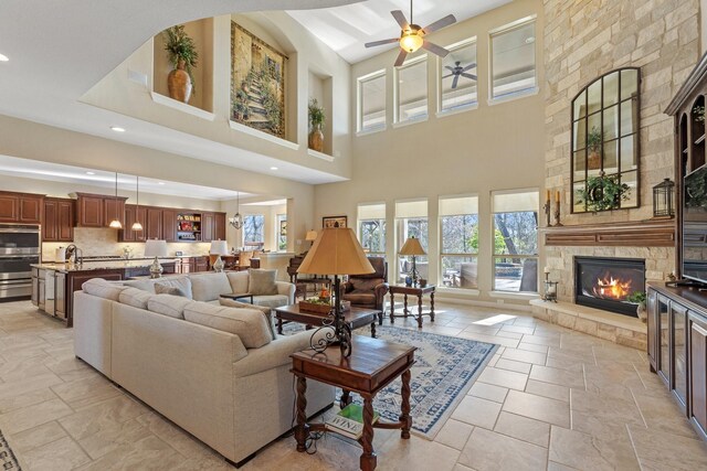 5131 Rowley Falls Ln, Sugar Land, TX 77479 - living room with ceiling fan, healthy amount of natural light, a stone fireplace, stone tile flooring, and a towering ceiling