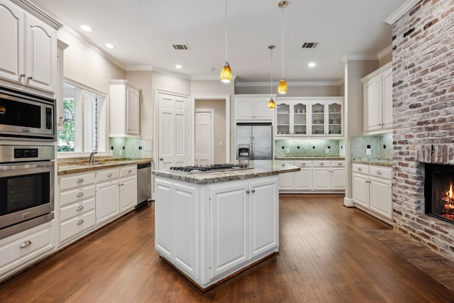 12126 Oak Park Dr, Houston, TX 77070 - kitchen featuring stainless steel appliances, a kitchen island, white cabinets, decorative backsplash, and crown molding