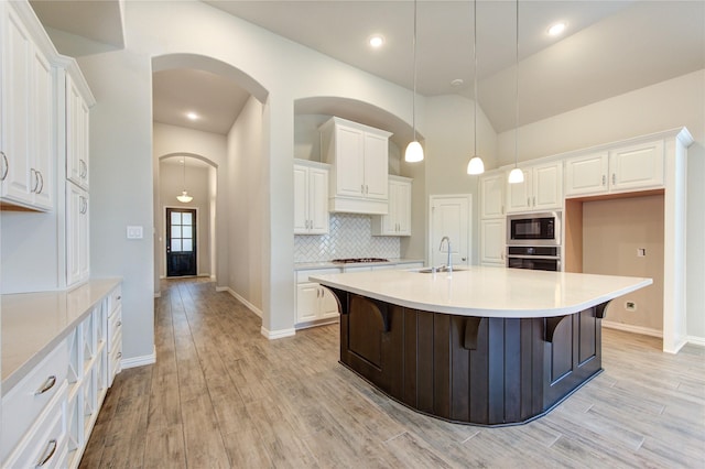 28418 Asher Falls Ln, Fulshear, TX 77441 - kitchen with built in microwave, a sink, oven, arched walkways, and white cabinets