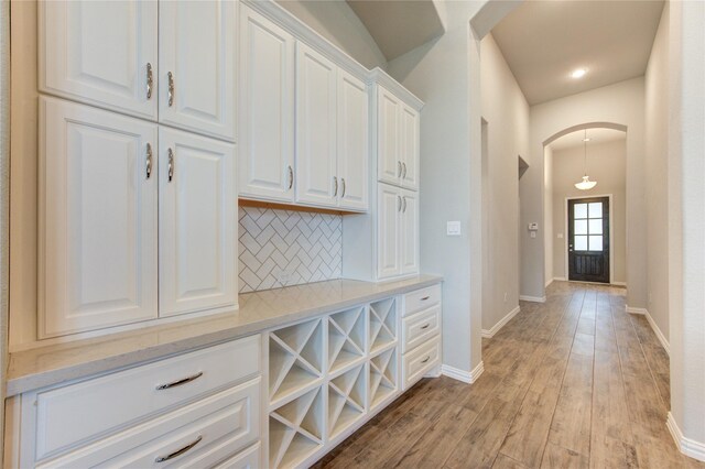 28418 Asher Falls Ln, Fulshear, TX 77441 - interior space with arched walkways, tasteful backsplash, light wood finished floors, and baseboards