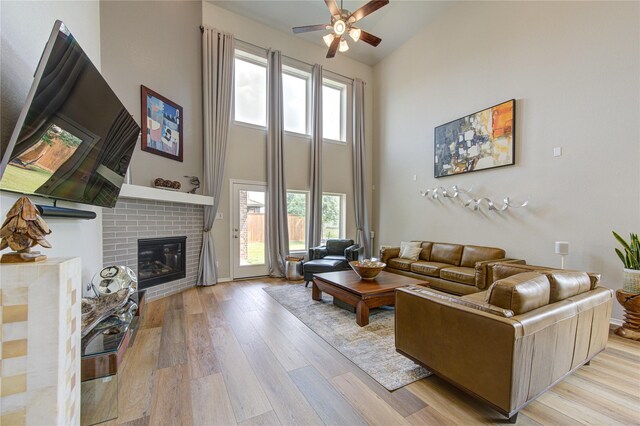 11702 Twin Creeks Hill Dr, Cypress, TX 77433 - living room with a high ceiling, a ceiling fan, light wood finished floors, and a fireplace