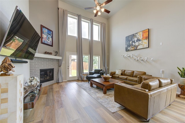 11702 Twin Creeks Hill Dr, Cypress, TX 77433 - living room with a high ceiling, a ceiling fan, light wood finished floors, and a fireplace