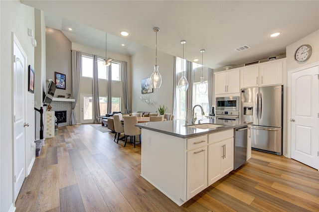 11702 Twin Creeks Hill Dr, Cypress, TX 77433 - kitchen featuring appliances with stainless steel finishes, a sink, light wood-type flooring, a brick fireplace, and recessed lighting
