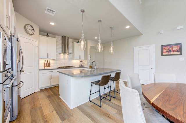 11702 Twin Creeks Hill Dr, Cypress, TX 77433 - kitchen featuring wall chimney exhaust hood, a sink, stainless steel appliances, light wood-type flooring, and a kitchen bar