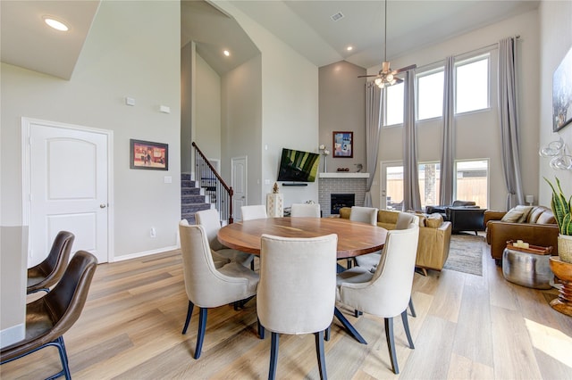 11702 Twin Creeks Hill Dr, Cypress, TX 77433 - dining area with high vaulted ceiling, a fireplace, stairway, light wood-style floors, and baseboards