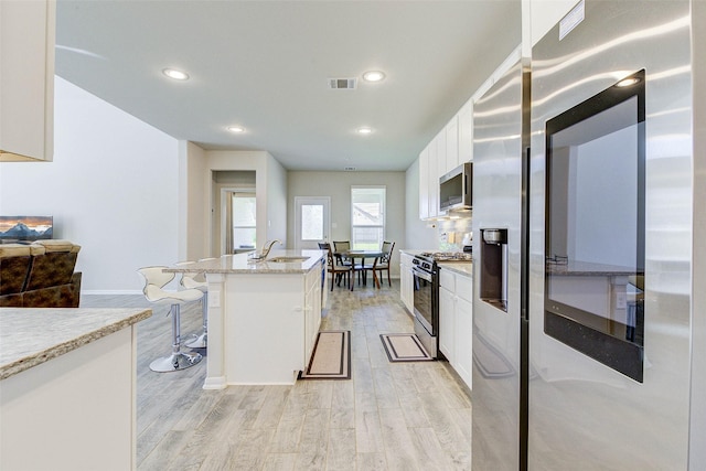 21430 Costalinda Dr, Cypress, TX 77433 - kitchen featuring stainless steel appliances, white cabinetry, light wood-style flooring, a center island with sink, and recessed lighting