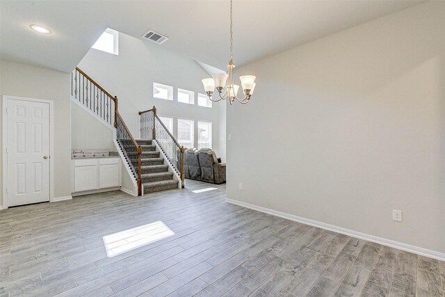 21430 Costalinda Dr, Cypress, TX 77433 - empty room featuring stairway, light wood-style flooring, a chandelier, baseboards, and a towering ceiling