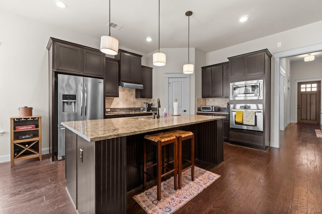 122 Cherry Oak Ln, Montgomery, TX 77316 - kitchen featuring stainless steel appliances, decorative backsplash, light stone countertops, dark brown cabinetry, and recessed lighting