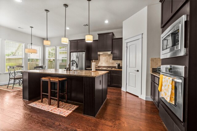 122 Cherry Oak Ln, Montgomery, TX 77316 - kitchen with appliances with stainless steel finishes, dark wood-type flooring, decorative backsplash, a kitchen bar, and recessed lighting