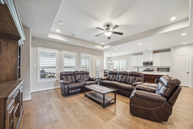 538 Still Water Ridge Ln, Sealy, TX 77474 - living room featuring a tray ceiling, ceiling fan, light wood-style flooring, baseboards, and recessed lighting