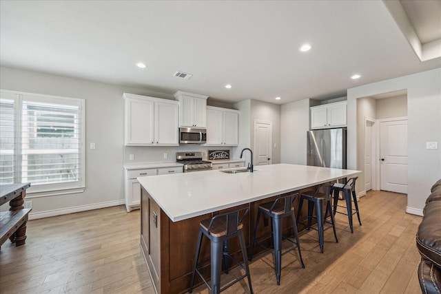 538 Still Water Ridge Ln, Sealy, TX 77474 - kitchen with appliances with stainless steel finishes, a sink, light wood finished floors, recessed lighting, and a kitchen breakfast bar