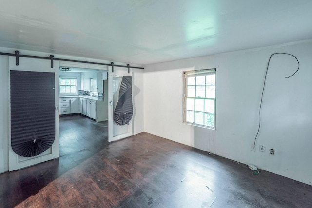7988 Joy St, Houston, TX 77028 - unfurnished room featuring a barn door and dark wood-style flooring