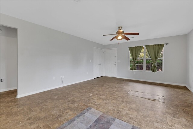 424 Baker Cir, Ames, TX 77575 - unfurnished room featuring ceiling fan, baseboards, and stone finish floors