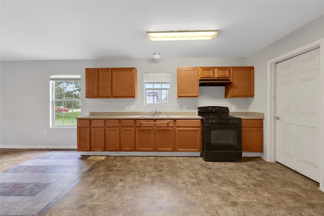 424 Baker Cir, Ames, TX 77575 - kitchen featuring black range with gas stovetop, under cabinet range hood, a sink, light countertops, and brown cabinetry