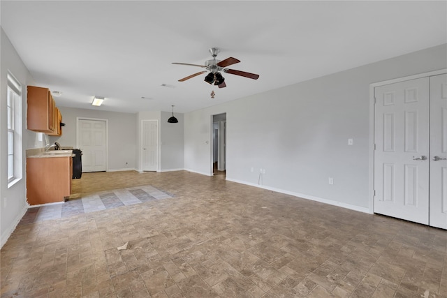424 Baker Cir, Ames, TX 77575 - unfurnished living room featuring a ceiling fan and baseboards