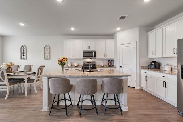 5732 Palm Flower Dr, Montgomery, TX 77316 - kitchen with stainless steel microwave, a sink, a center island with sink, a breakfast bar area, and recessed lighting