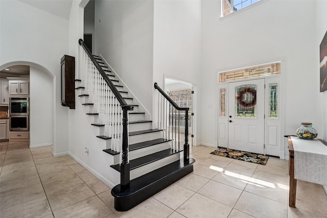 21885 Lost Mdw, New Caney, TX 77357 - entrance foyer featuring a high ceiling, arched walkways, light tile patterned floors, stairway, and baseboards