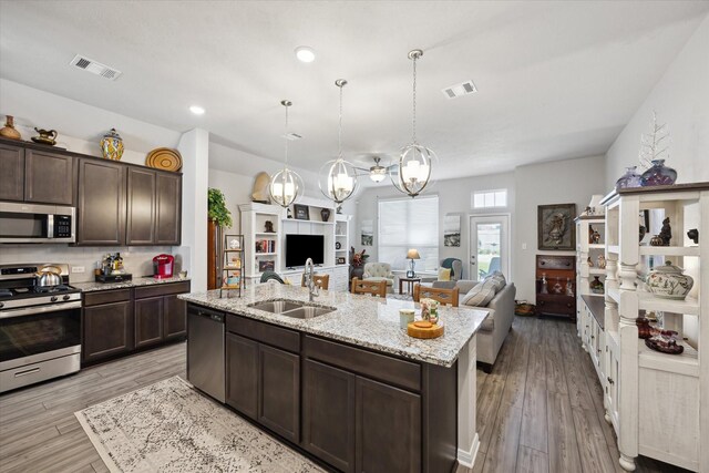 1010 Old Vine Rd, Brenham, TX 77833 - kitchen with appliances with stainless steel finishes, a sink, open floor plan, dark brown cabinetry, and a chandelier