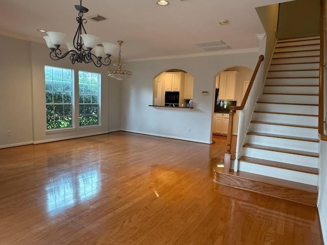 7222 Harmony Cv, Houston, TX 77036 - unfurnished living room featuring baseboards, stairs, crown molding, wood finished floors, and a chandelier