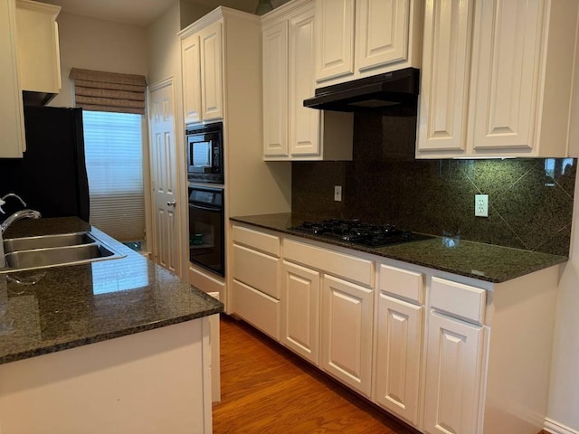 7222 Harmony Cv, Houston, TX 77036 - kitchen with black appliances, a sink, under cabinet range hood, white cabinets, and decorative backsplash