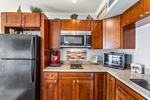 6300 Seawall Blvd Unit 9115, Galveston, TX 77551 - kitchen with freestanding refrigerator, stainless steel microwave, a textured ceiling, light stone counters, and crown molding