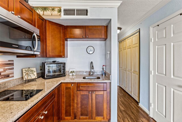 6300 Seawall Blvd Unit 9115, Galveston, TX 77551 - kitchen with stainless steel microwave, black electric stovetop, a sink, dark wood-style flooring, and ornamental molding