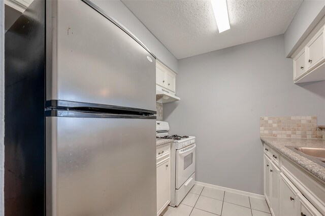 1016 Tri Oaks Ln Unit 92, Houston, TX 77043 - kitchen with white range with gas cooktop, freestanding refrigerator, under cabinet range hood, white cabinets, and a textured ceiling