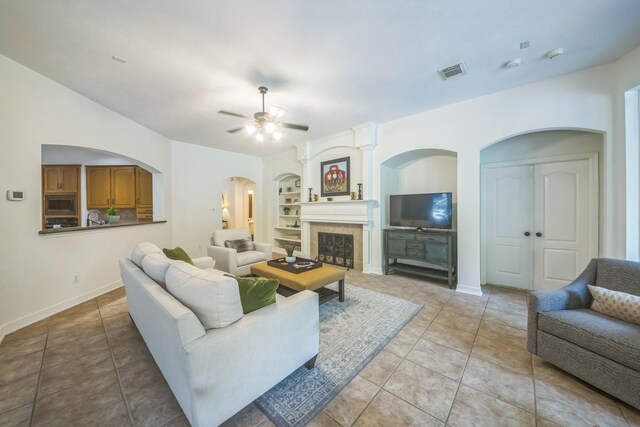 17407 W Blooming Rose Ct, Cypress, TX 77429 - living area with light tile patterned floors, built in shelves, a ceiling fan, and arched walkways