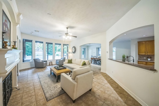 17407 W Blooming Rose Ct, Cypress, TX 77429 - living room with ceiling fan, arched walkways, a fireplace, and baseboards