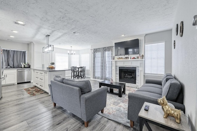 3031 Creek Manor Dr, Houston, TX 77339 - living room featuring light wood-type flooring, a textured ceiling, a chandelier, a fireplace, and recessed lighting