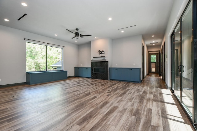 11007 Olde Mint House Ln, Tomball, TX 77375 - unfurnished living room with plenty of natural light, wood finished floors, a glass covered fireplace, ceiling fan, and recessed lighting